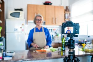 close up of camera filming a mature woman or senior cooking and doing live or video